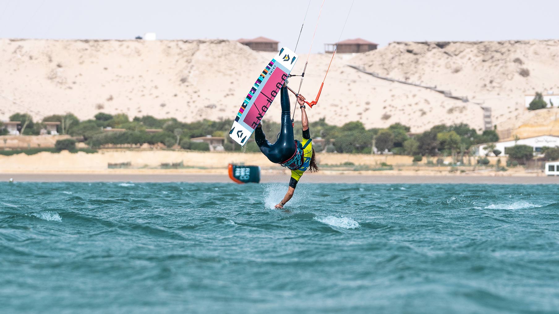 kitesurfer doing a trick and he is touching the water with his hand