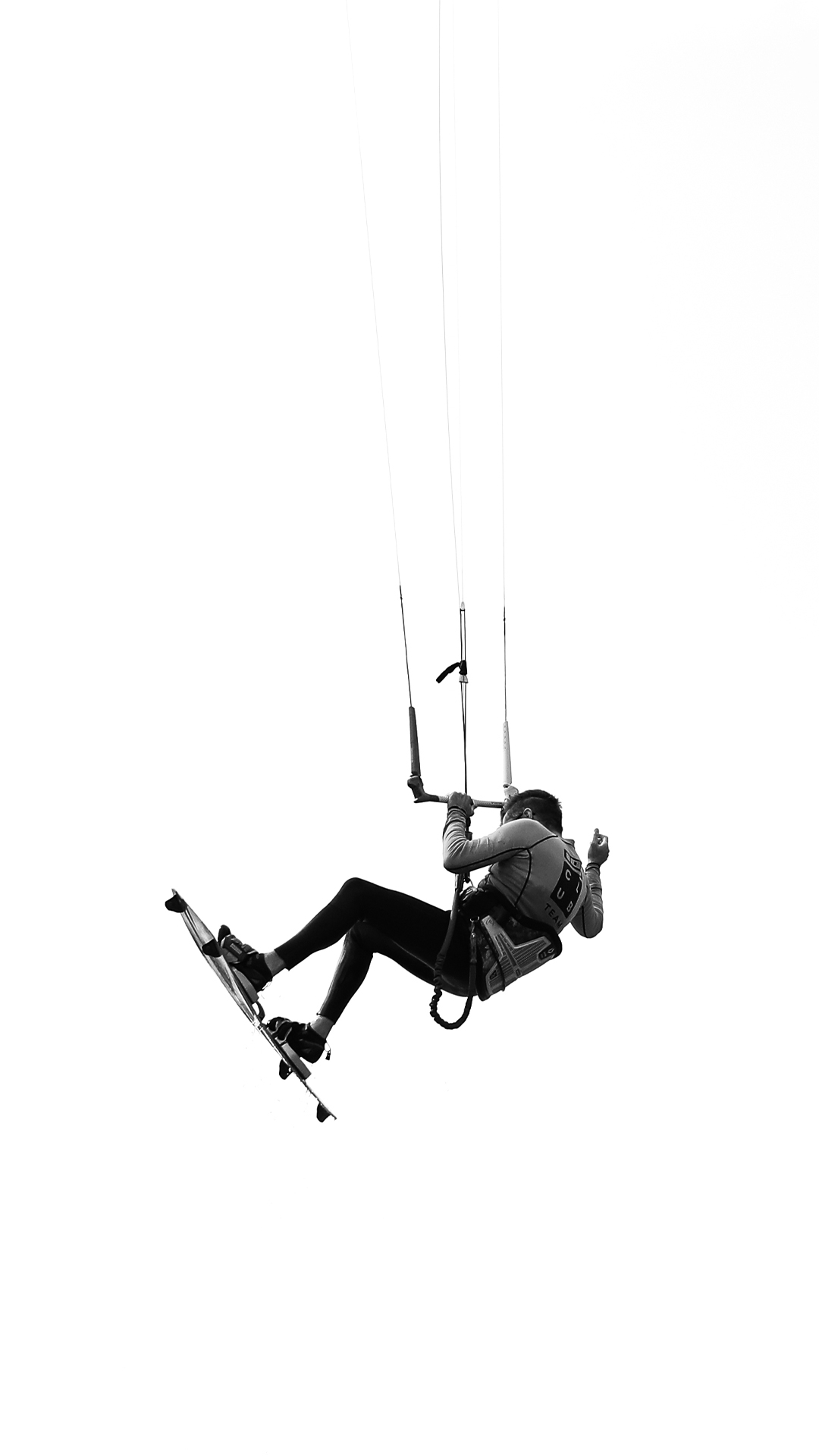 photo en noir et blanc d'un kitesurfer survolant le ciel 