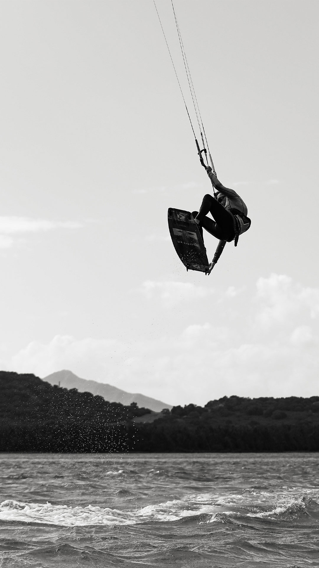 black and white picture about kitesurfer going down to the sky after doing a big jump with his kite