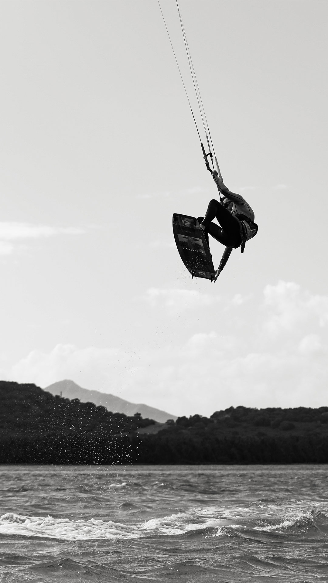 Schwarz-Weiß-Foto eines Kitesurfers, der mit seiner Kitesurfing-Ausrüstung am Le More Spot auf Mauritius springt. 