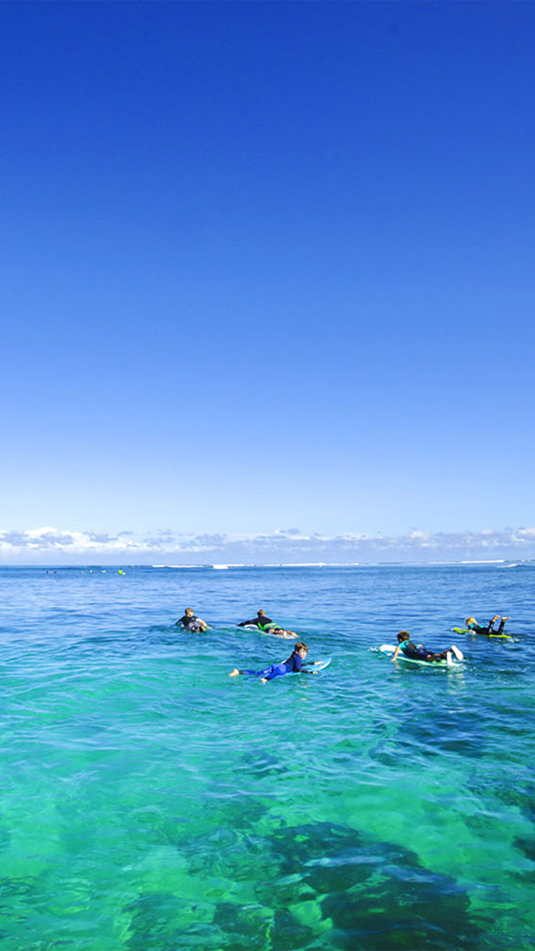 Small surfers waiting in front of the wave spot in Le Morne zone, Mauritius