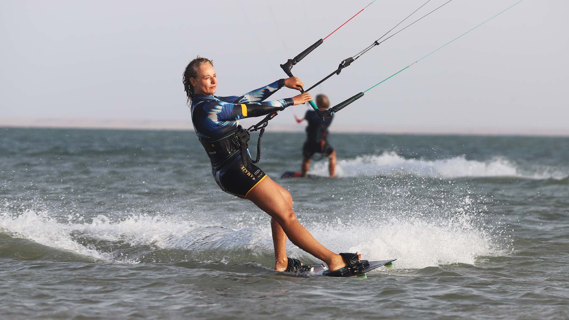 femme kitesurfeuse sur l'eau qui sourit