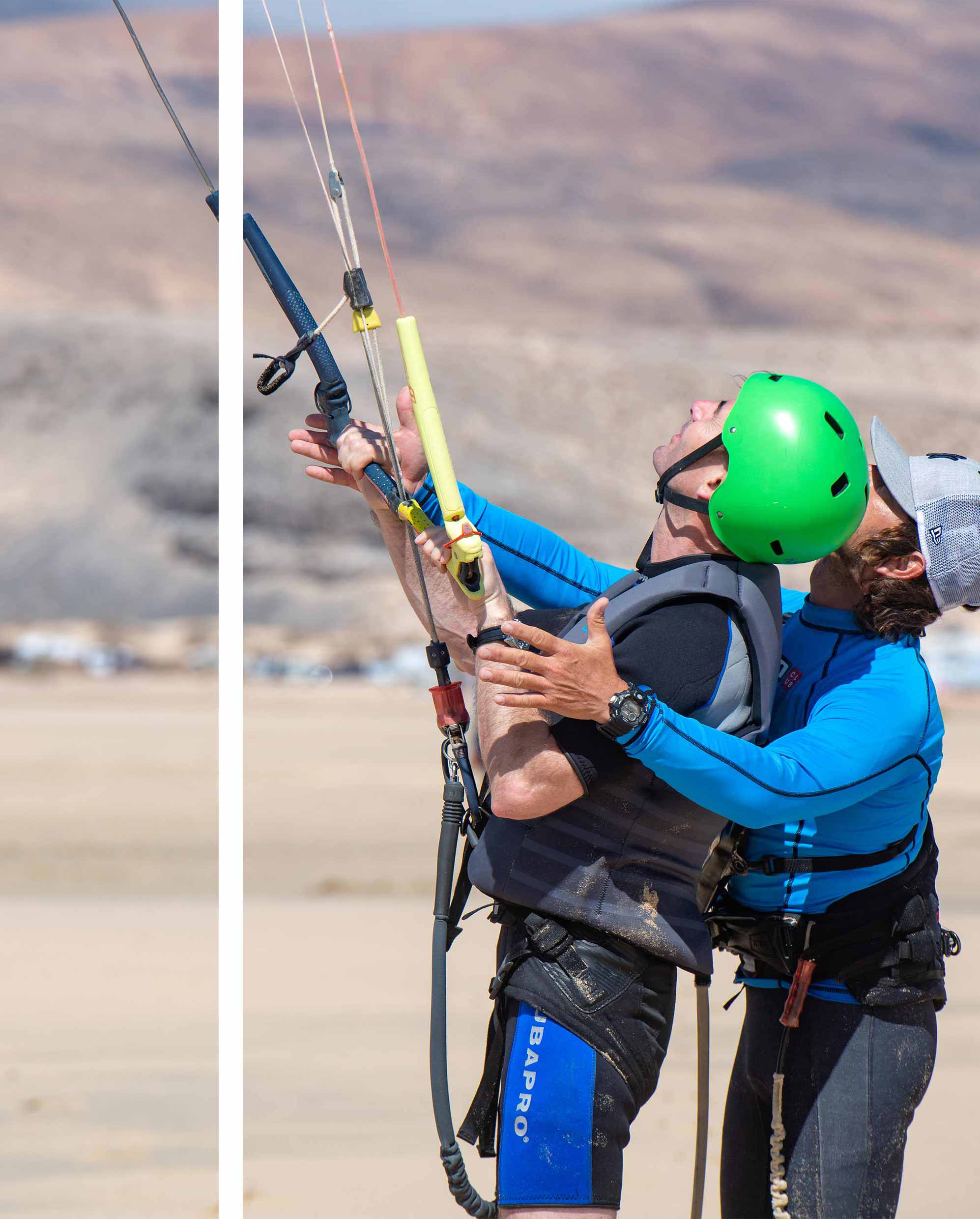 Secuencia de imágenes en las que un instructeur de kitesurf se cae realizando unos de los trucos para enseñárselo a sus estudiantes durante una clase   Devant un drapeau indiquant la zone de cours de kitesurf et au loin un étudiant marchant en tenue de sécurité.  Un instructeur enseignant comment attacher le leash au harnais de kitesurf, un étudiant du cours de kitesurf tenant un cerf-volant et un instructeur tenant une planche de kitesurf afin d'entrer dans l'eau pour naviguer.  Un étudiant du cours de kitesurf est au niveau 2, nageant dans l'eau en même temps qu'il contrôle son cerf-volant.   Un instructeur de kitesurf de Ion Club Centers enseigne le water star à sa petite fille.   Un instructeur enseigne à son élève comment piloter le cerf-volant sur la plage de sable. 