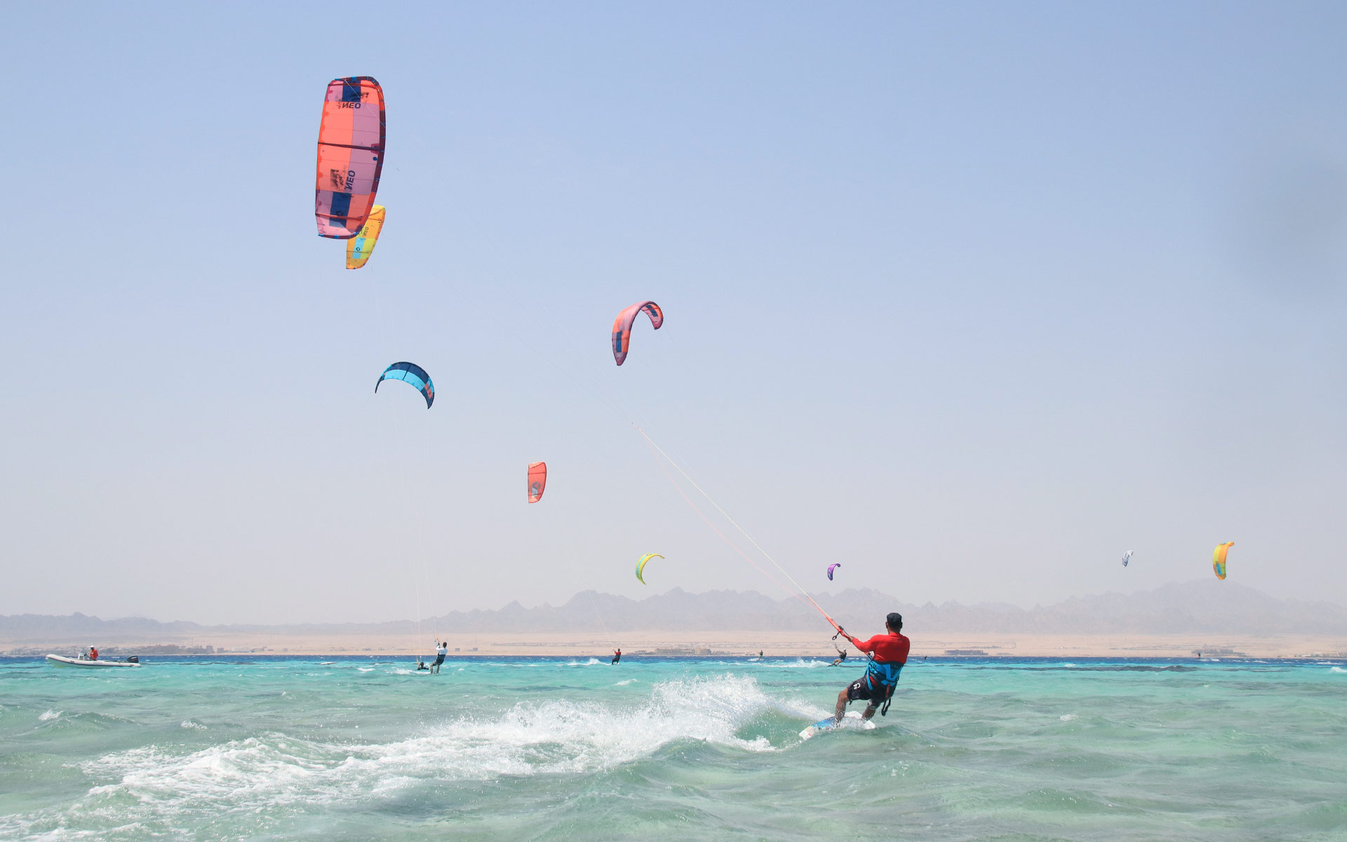 On the horizon many kitesurfers are sailing the waters of the Red Sea and in the foreground is one of the instructors of the Ion Club Safaga. 