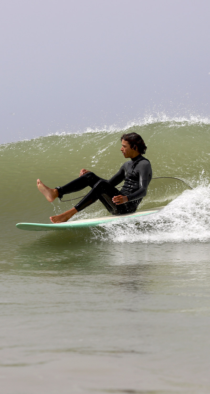 A young man has fun surfing a wave sitting on his surfboard at the on Club Lassarga spot.