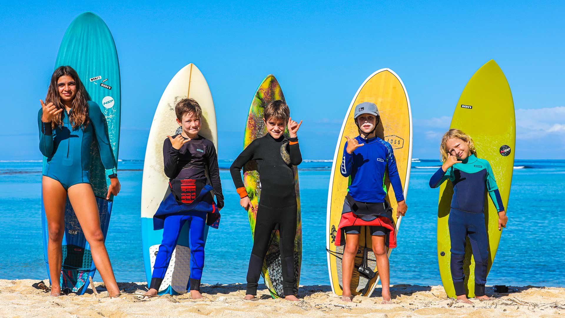 Un groupe d'enfants pose joyeusement pour une photo avec leur planche de surf après le cours de la journée. 