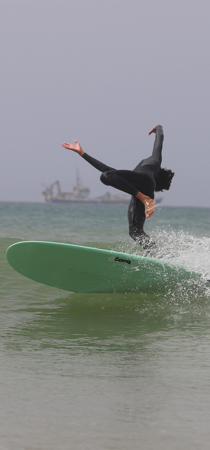 ein Junge, der surfen lernt, fällt beim Versuch, eine Welle zu surfen, von seinem Brett 