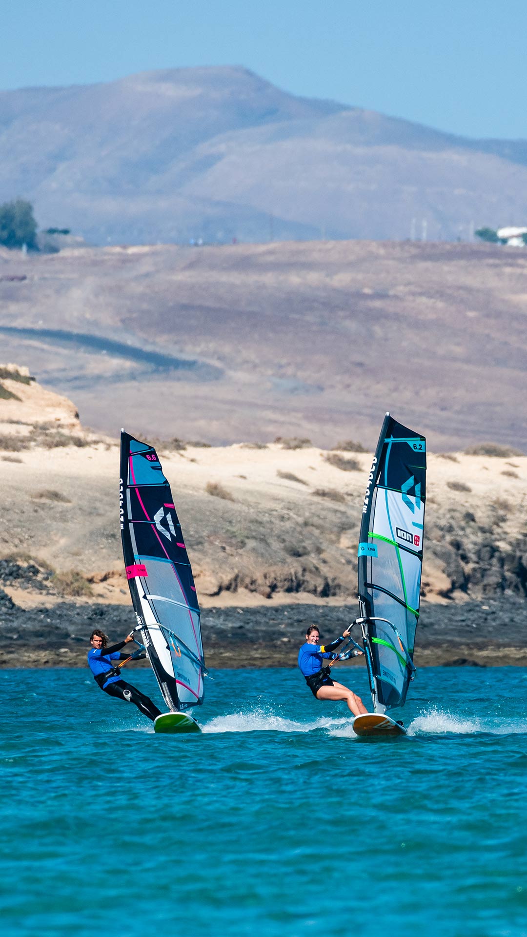 Windsurfing-team-sesion-in-Costa-Calma-Sot-The-Maui-of-Europe-2022 Twee leden van het Ion Club Costa Calma team genieten van een zeilsessie in de wateren van de Atlantische Oceaan waar ook Maui van geniet.