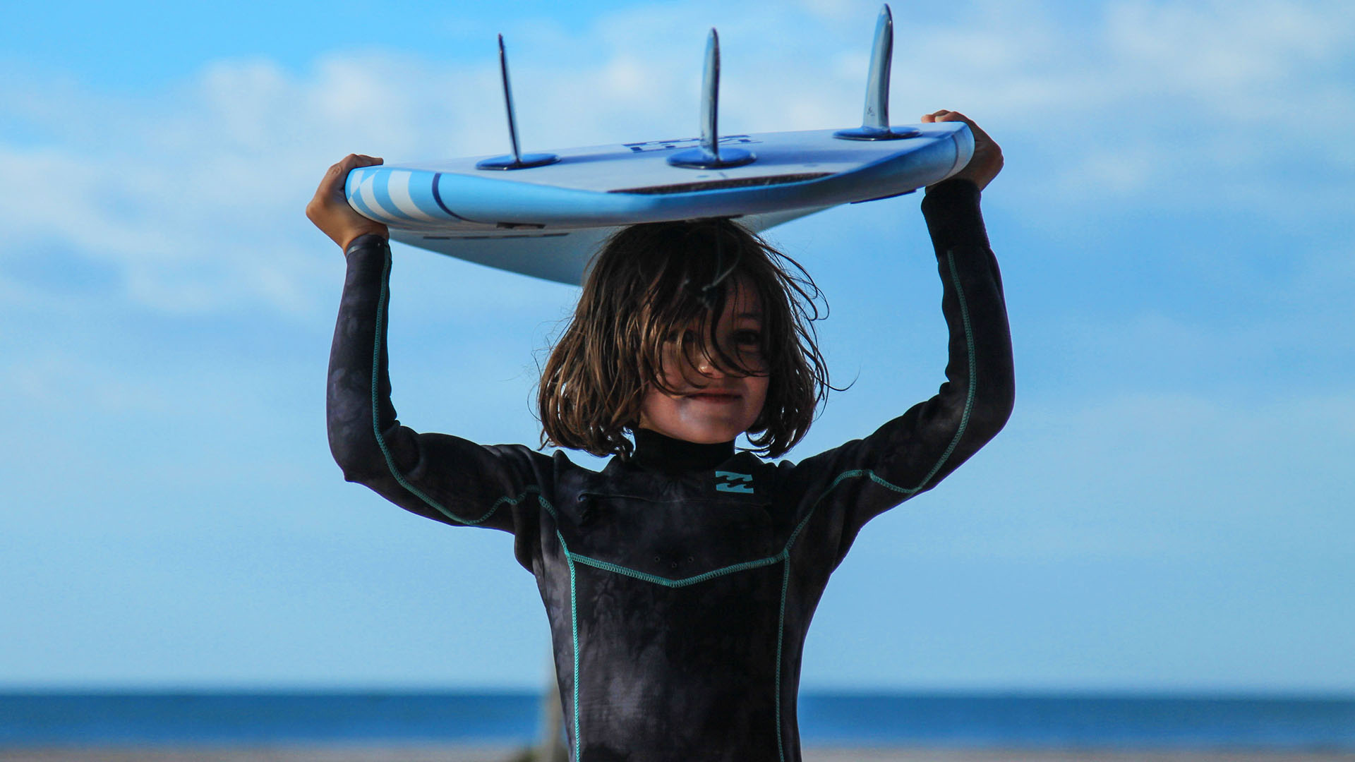child who doing surf with a blue sky