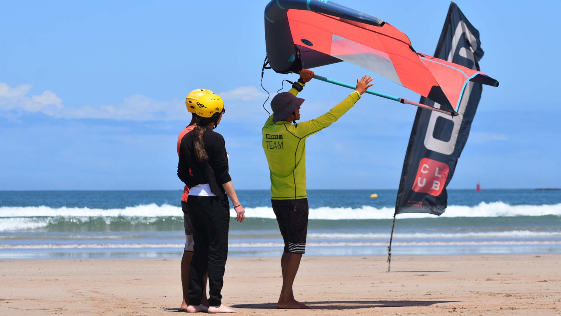 beach with blue water and a wingsurf lesson