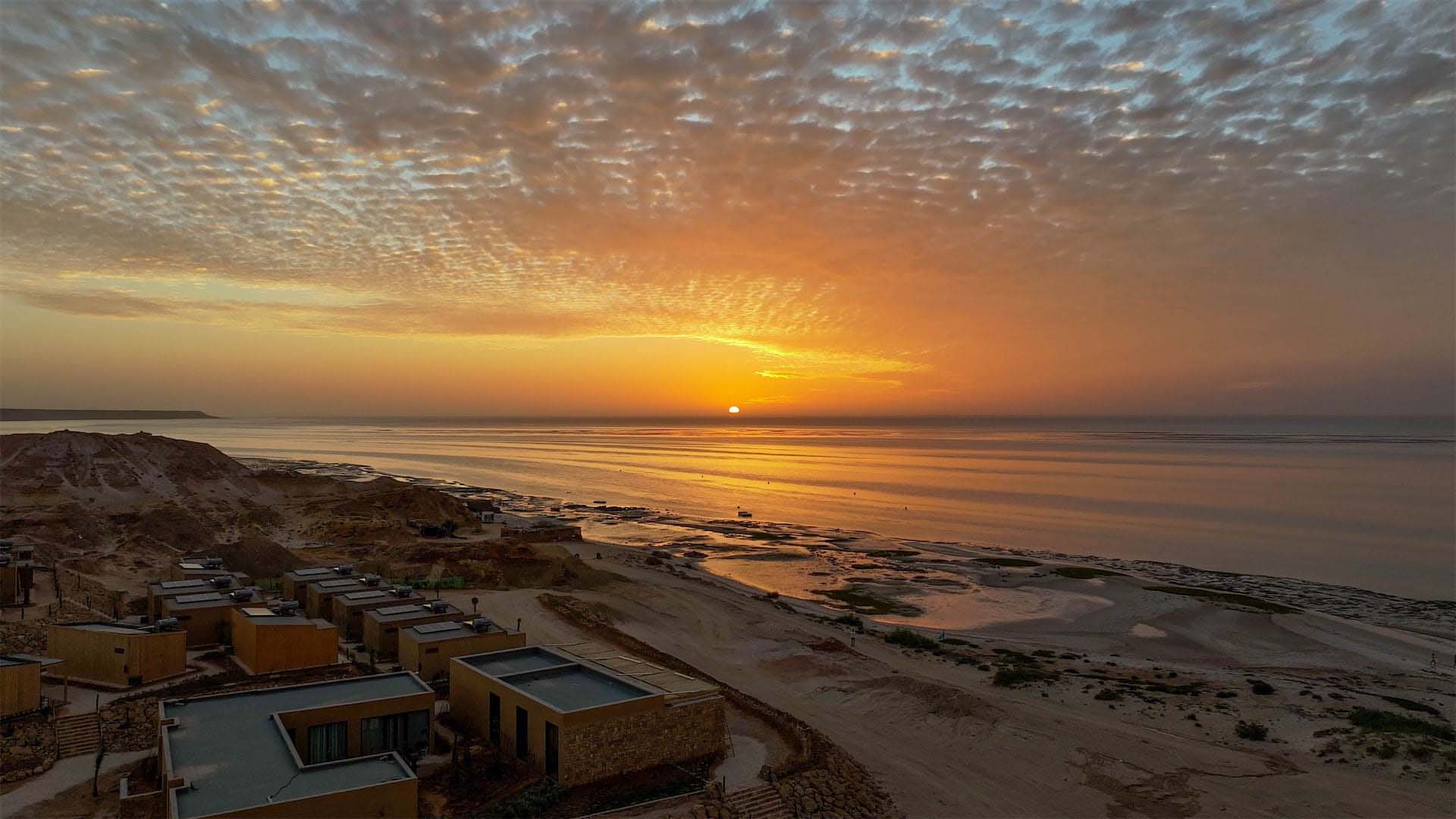 sunset in the middle of the desert with the ocean