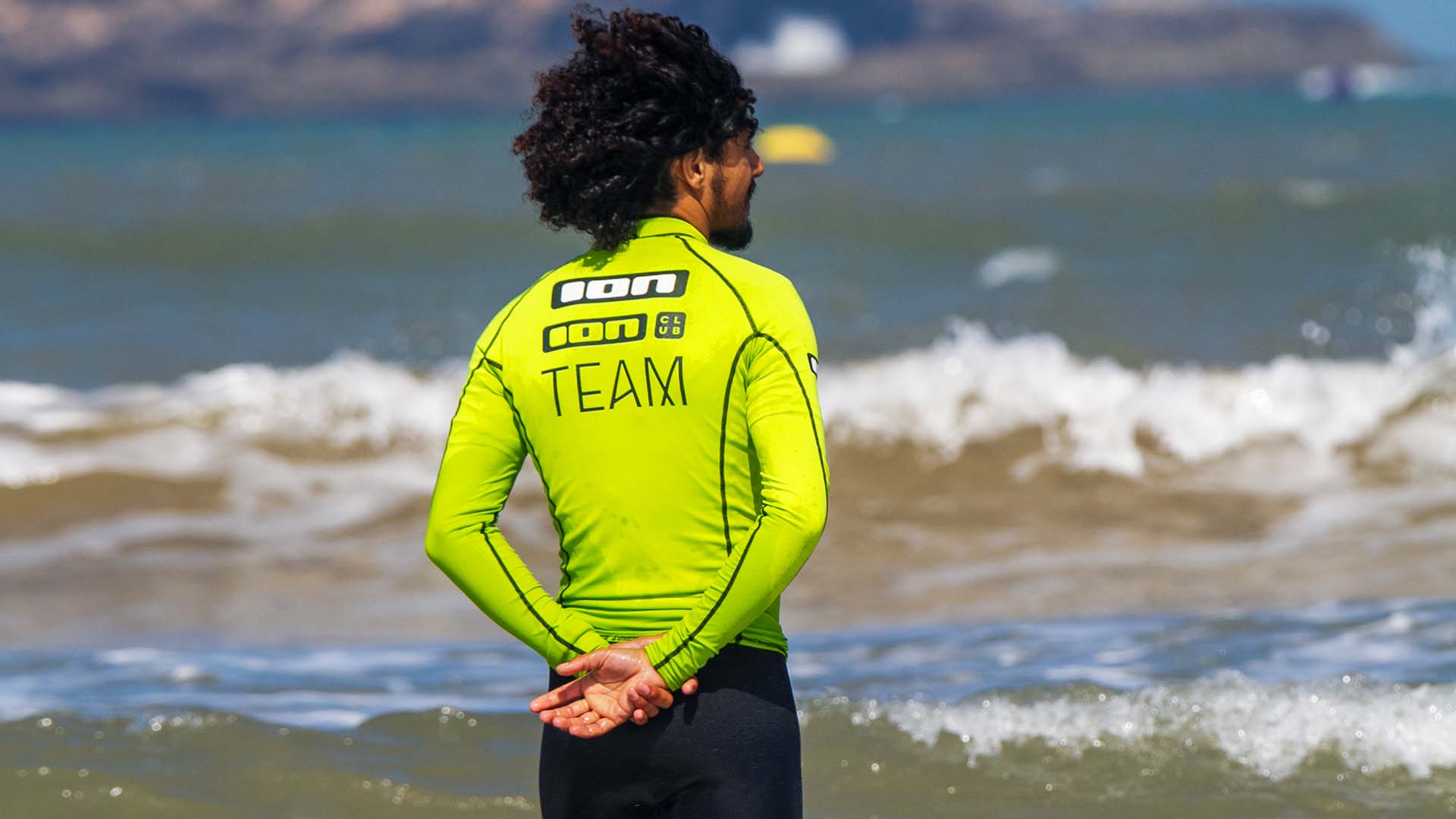 man with an ion wetsuit and a kite on the beach