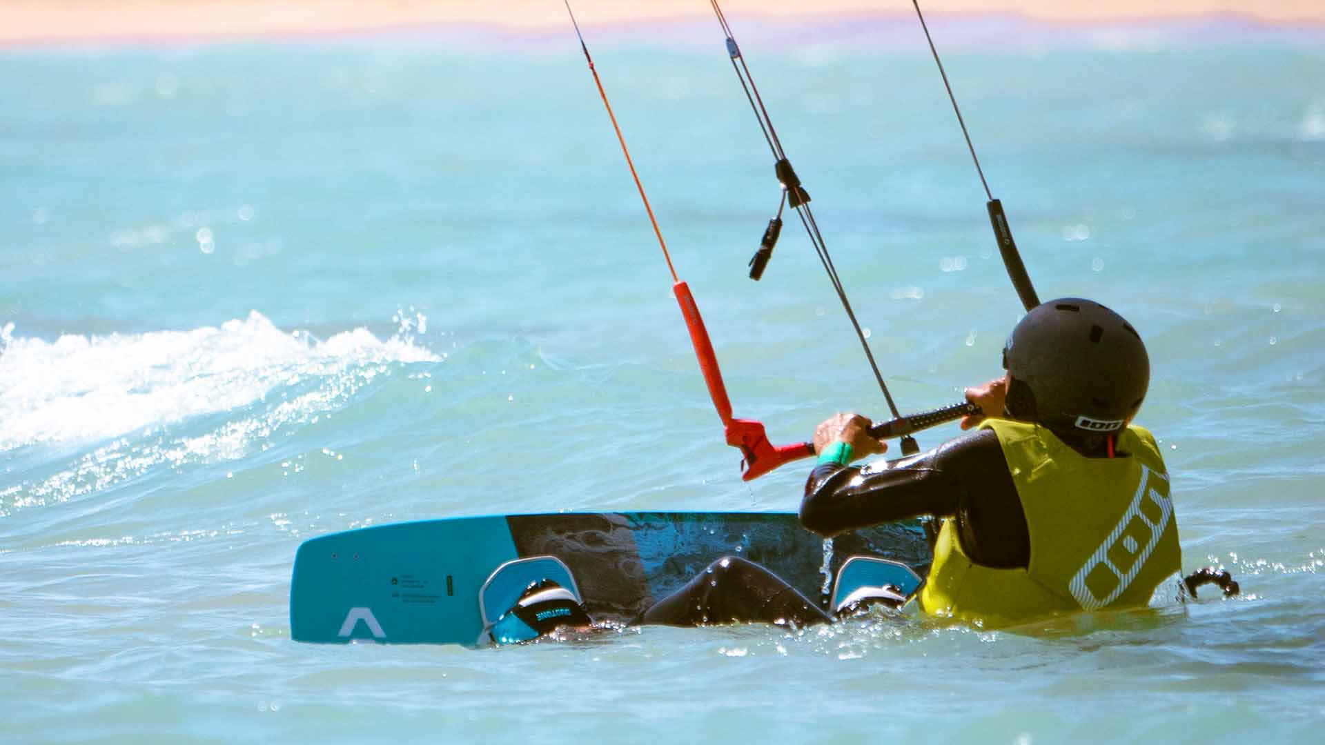 man with an ion wetsuit and a kite on the beach